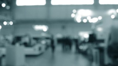 Binada yürüyen insanlar. Duvarları, zemini, tavan lambaları olan bir bina. İçerideki insanların siluetleri. Bir sürü insan yürüyor. Erkekler ve kadınlar uzun salonda. Sergi merkezi. Bulanık arkaplan