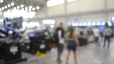 Binada yürüyen insanlar. Duvarları, zemini, tavan lambaları olan bir bina. İçerideki insanların siluetleri. Bir sürü insan yürüyor. Erkekler ve kadınlar uzun salonda. Sergi merkezi. Bulanık arkaplan