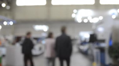 Binada yürüyen insanlar. Duvarları, zemini, tavan lambaları olan bir bina. İçerideki insanların siluetleri. Bir sürü insan yürüyor. Erkekler ve kadınlar uzun salonda. Sergi merkezi. Bulanık arkaplan