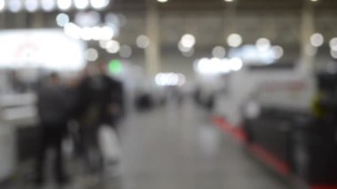 Binada yürüyen insanlar. Duvarları, zemini, tavan lambaları olan bir bina. İçerideki insanların siluetleri. Bir sürü insan yürüyor. Erkekler ve kadınlar uzun salonda. Sergi merkezi. Bulanık arkaplan