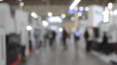 Binada yürüyen insanlar. Duvarları, zemini, tavan lambaları olan bir bina. İçerideki insanların siluetleri. Bir sürü insan yürüyor. Erkekler ve kadınlar uzun salonda. Sergi merkezi. Bulanık arkaplan