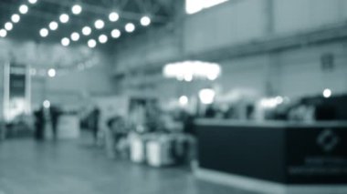 Binada yürüyen insanlar. Duvarları, zemini, tavan lambaları olan bir bina. İçerideki insanların siluetleri. Bir sürü insan yürüyor. Erkekler ve kadınlar uzun salonda. Sergi merkezi. Bulanık arkaplan