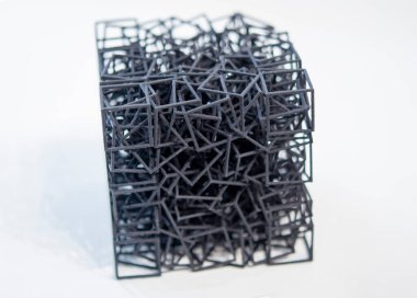 Erimiş siyah plastikten çıkan üç boyutlu yazıcıya beyaz izole arkaplana basılmış nesne. Plastik ağ küp şekli 3D yazıcıda oluşturuldu. 3D yazıcı Ek 3D yazıcı teknolojisi tarafından basılan küçük form