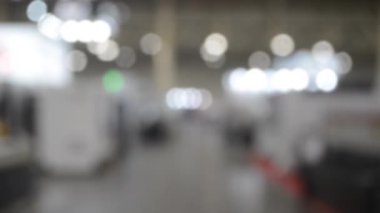 Binada yürüyen insanlar. Duvarları, zemini, tavan lambaları olan bir bina. İçerideki insanların siluetleri. Bir sürü insan yürüyor. Erkekler ve kadınlar uzun salonda. Sergi merkezi. Bulanık arkaplan