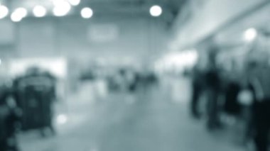 Binada yürüyen insanlar. Duvarları, zemini, tavan lambaları olan bir bina. İçerideki insanların siluetleri. Bir sürü insan yürüyor. Erkekler ve kadınlar uzun salonda. Sergi merkezi. Bulanık arkaplan