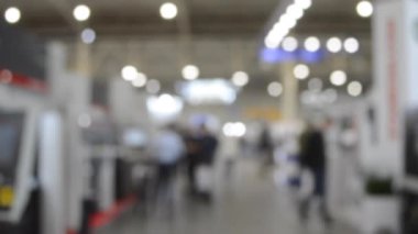 Binada yürüyen insanlar. Duvarları, zemini, tavan lambaları olan bir bina. İçerideki insanların siluetleri. Bir sürü insan yürüyor. Erkekler ve kadınlar uzun salonda. Sergi merkezi. Bulanık arkaplan