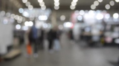 Binada yürüyen insanlar. Duvarları, zemini, tavan lambaları olan bir bina. İçerideki insanların siluetleri. Bir sürü insan yürüyor. Erkekler ve kadınlar uzun salonda. Sergi merkezi. Bulanık arkaplan