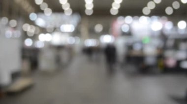 Binada yürüyen insanlar. Duvarları, zemini, tavan lambaları olan bir bina. İçerideki insanların siluetleri. Bir sürü insan yürüyor. Erkekler ve kadınlar uzun salonda. Sergi merkezi. Bulanık arkaplan