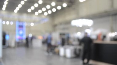 Binada yürüyen insanlar. Duvarları, zemini, tavan lambaları olan bir bina. İçerideki insanların siluetleri. Bir sürü insan yürüyor. Erkekler ve kadınlar uzun salonda. Sergi merkezi. Bulanık arkaplan