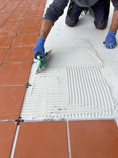 worker spreads the cement glue before applying the ceramic tiles