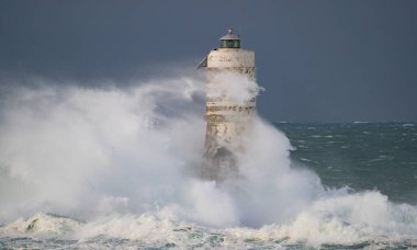 the lighthouse of the mangiabarche in calasetta, in southern sardinia, submerged by the waves of the stormy sea