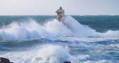 the lighthouse of the mangiabarche in calasetta, in southern sardinia, submerged by the waves of the stormy sea