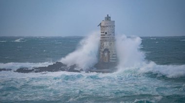 the lighthouse of the mangiabarche in calasetta, in southern sardinia, submerged by the waves of the stormy sea