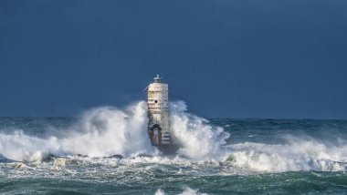 the lighthouse of the mangiabarche in calasetta, in southern sardinia, submerged by the waves of the stormy sea