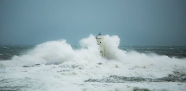 the lighthouse of the mangiabarche in calasetta, in southern sardinia, submerged by the waves of the stormy sea