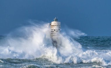 the lighthouse of the mangiabarche in calasetta, in southern sardinia, submerged by the waves of the stormy sea