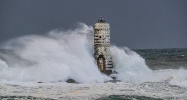 the lighthouse of the mangiabarche in calasetta, in southern sardinia, submerged by the waves of the stormy sea