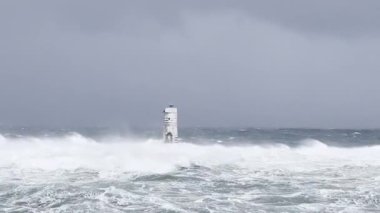 the lighthouse of the mangiabarche in calasetta, in southern sardinia, submerged by the waves of the stormy sea