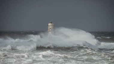 the lighthouse of the mangiabarche in calasetta, in southern sardinia, submerged by the waves of the stormy sea