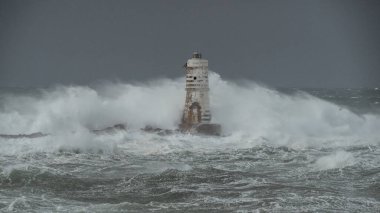 the lighthouse of the mangiabarche in calasetta, in southern sardinia, submerged by the waves of the stormy sea