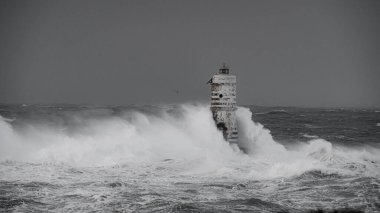 the lighthouse of the mangiabarche in calasetta, in southern sardinia, submerged by the waves of the stormy sea