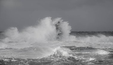 the lighthouse of the mangiabarche in calasetta, in southern sardinia, submerged by the waves of the stormy sea