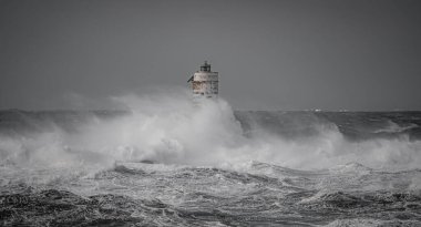 the lighthouse of the mangiabarche in calasetta, in southern sardinia, submerged by the waves of the stormy sea