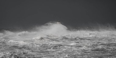 the lighthouse of the mangiabarche in calasetta, in southern sardinia, submerged by the waves of the stormy sea