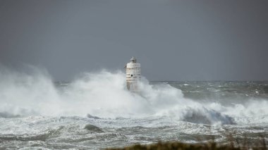 the lighthouse of the mangiabarche in calasetta, in southern sardinia, submerged by the waves of the stormy sea