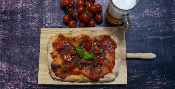 Roman pinsa with tomato mozzarella basil capers anchovies Neapolitan type