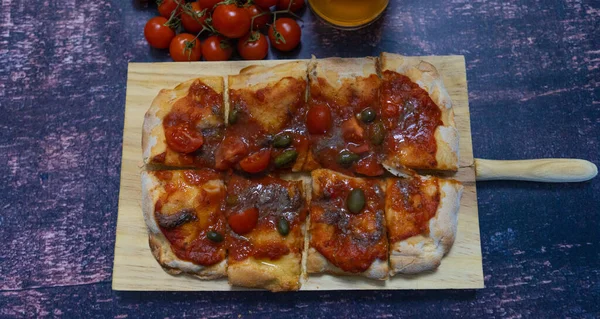Roman pinsa with tomato mozzarella basil capers anchovies Neapolitan type