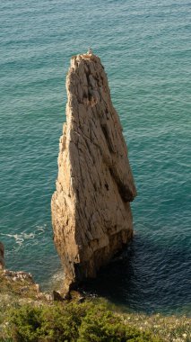 Kartal Yuvası, Sardunya 'nın batı kıyısının karakteristik yığınlarından biridir. Arka planda ise güzel kristal deniz Buggerru.