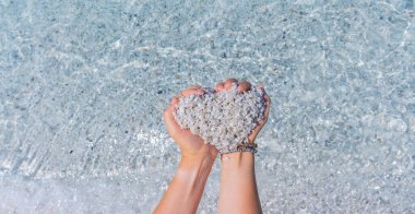 woman's hands forming a heart with the crystalline sand of is arutas beach clipart