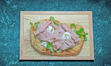 Roma pinsa 'sı, klasik İtalyan pizzasının bir çeşidi. Mortadella, stracciatella ve kuzu marulu ve şam fıstıklı.