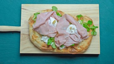 Roma pinsa 'sı, klasik İtalyan pizzasının bir çeşidi. Mortadella, stracciatella ve kuzu marulu ve şam fıstıklı.