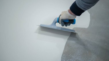 Beton zemine beyaz poliüretan reçinesi boyayan işçiler