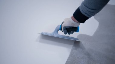 Beton zemine beyaz poliüretan reçinesi boyayan işçiler