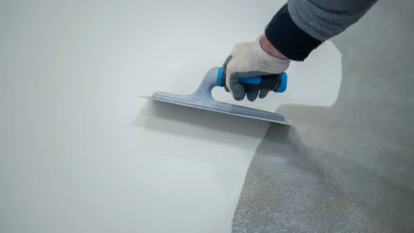 Beton zemine beyaz poliüretan reçinesi boyayan işçiler