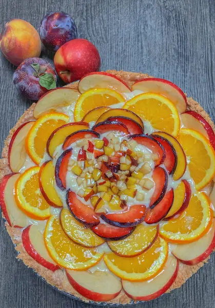 Piece of peach tart with fresh fruits on wooden table, top view