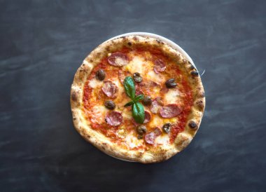 Kenarlı Napoli pizzası, baharatlı biber domates ve koyu arkaplanda mozzarella. Mozzarella 'lı pizza, domates sosu, acı biber.