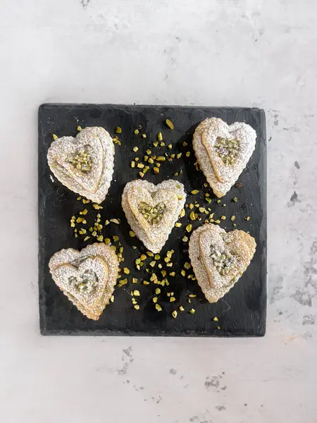 Valentine\'s Day sweets in the shape of a heart with pistachio cream and icing suga