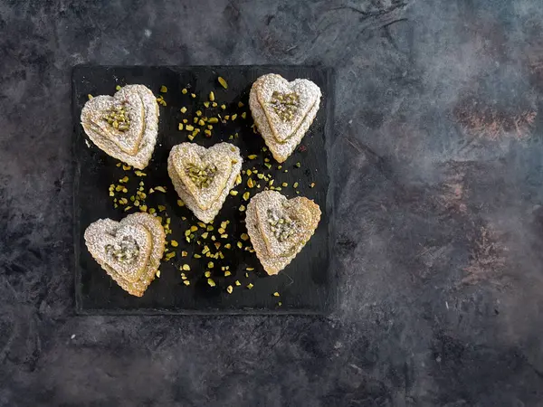 Valentine\'s Day sweets in the shape of a heart with pistachio cream and icing suga