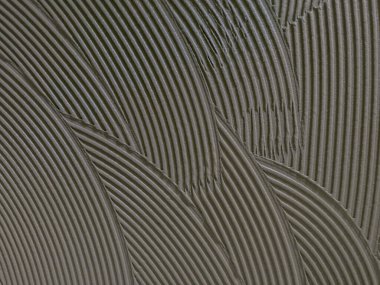 Döşemeye yapıştırıcı sürmüş. Seramiği almaya hazır.