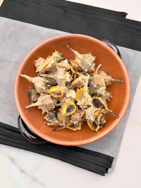 stock image Bolinus brandaris or murici, Plate of seafood morsels with lemon, boiled sea snails, Mediterranean Food