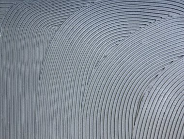 Beton duvar, zemine yapıştırıcı sürmüş. Eğri çizgileri olan modern gri arka plan.