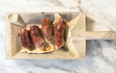 Tahta tepside dört ızgara sosis servis ediliyor.