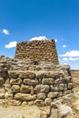 İtalya, Sardunya 'daki Nuraghe Piscu' nun görkemli harabeleri, canlı mavi gökyüzüne karşı dimdik ayakta duruyor, antik megalitik mimariyi gözler önüne seriyor.