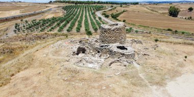İtalya, Sardunya 'daki Nuraghe Piscu' nun görkemli harabeleri, canlı mavi gökyüzüne karşı dimdik ayakta duruyor, antik megalitik mimariyi gözler önüne seriyor.