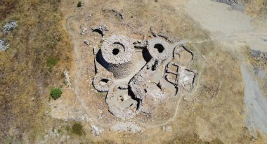 Majestic ruins of nuraghe Piscu in sardinia, italy, stand tall against a vibrant blue sky, showcasing ancient megalithic architecture clipart