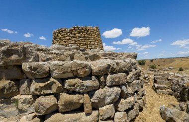 Majestic ruins of nuraghe Piscu in sardinia, italy, stand tall against a vibrant blue sky, showcasing ancient megalithic architecture clipart